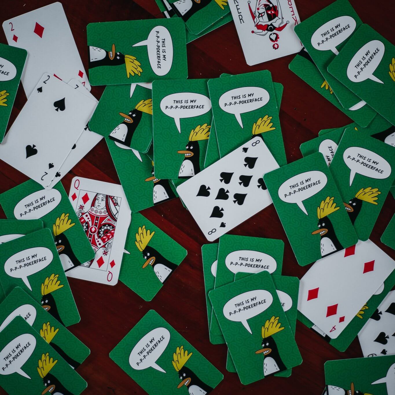 Custom poker-sized playing cards with penguin design scattered on table